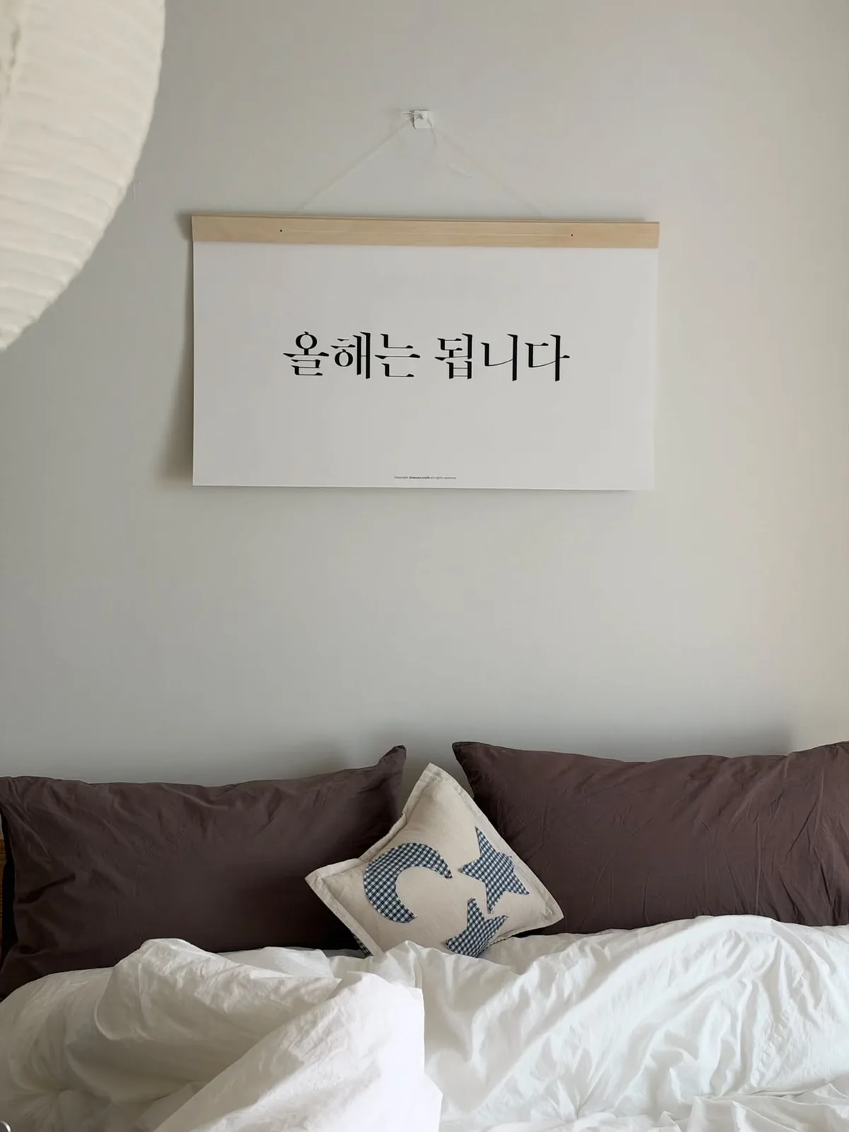 침대 위 벽에 걸린 표지, 올해는 됩니다