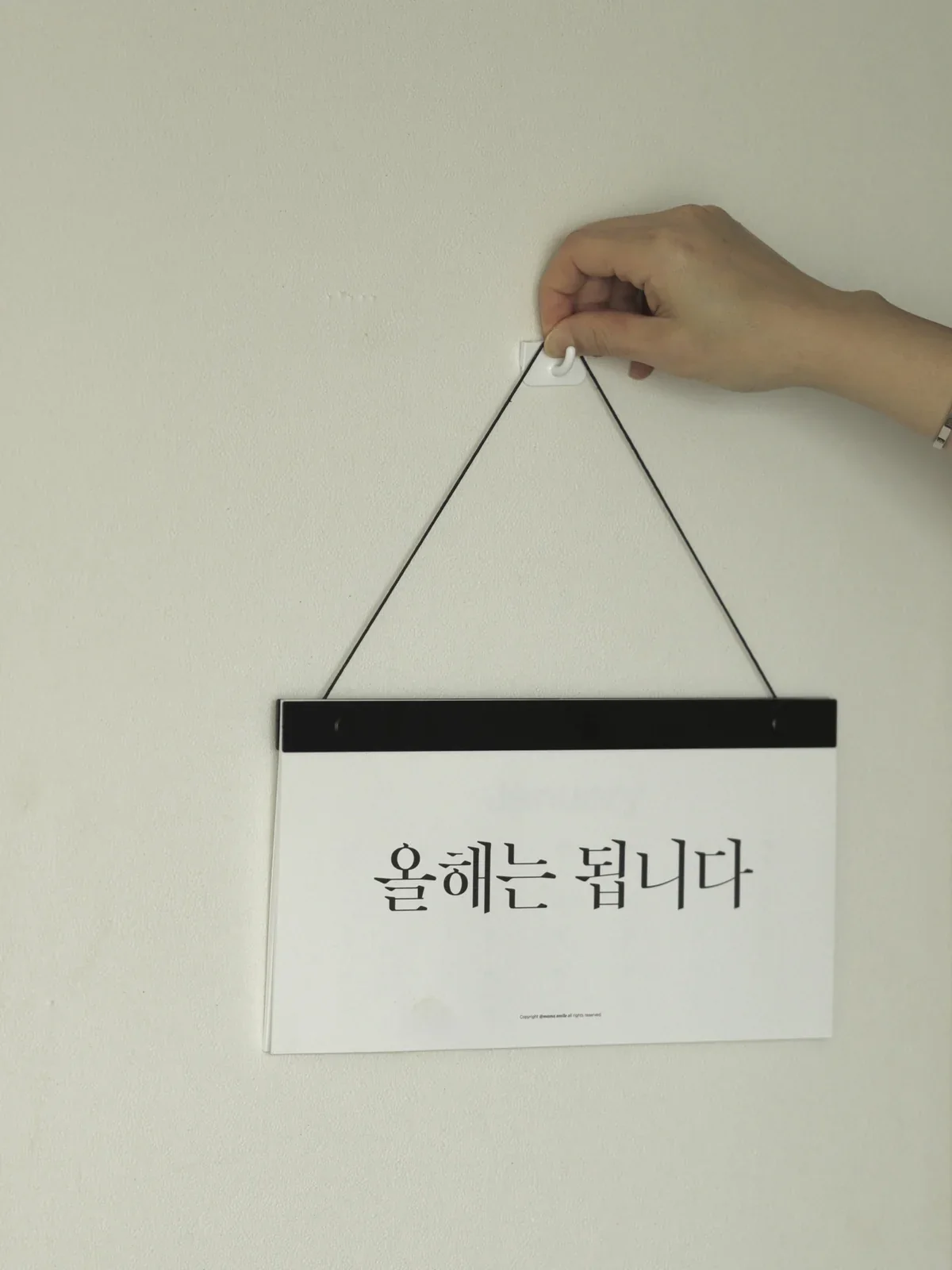 블랙 스틱 캘린더를 벽에 거는 손