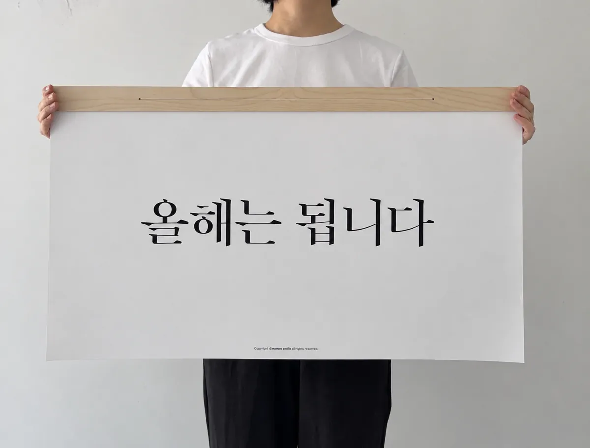 사람이 두 팔로 표지를 들어 보이는 장면, 올해는 됩니다