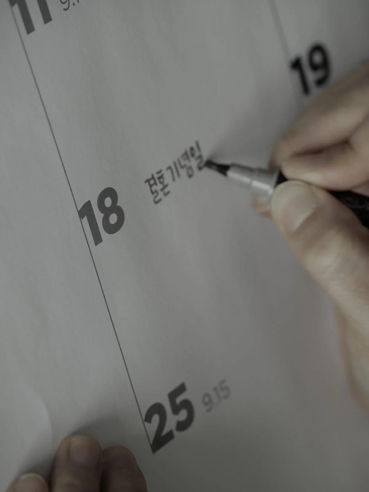 18일 옆에 펜으로 기념일을 적는 손